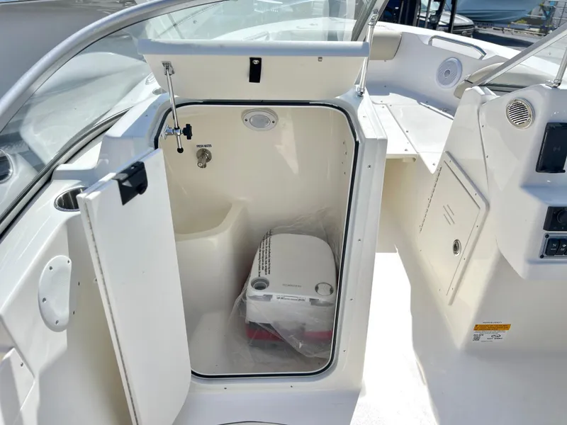 Slide: The Image of 2025 Key West 203 DFS boat interior with open storage compartment and portable toilet. - 18