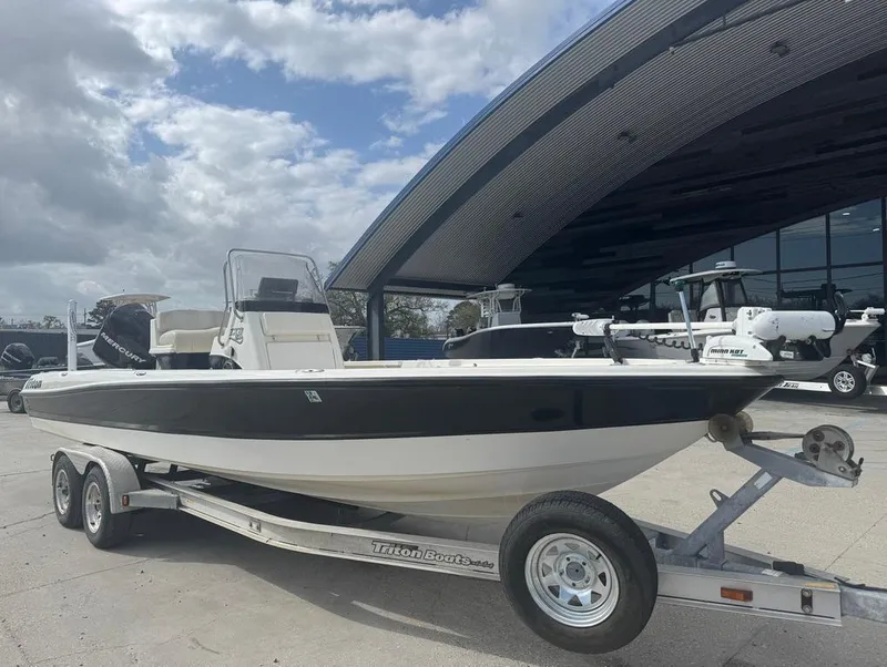 Slide: The Image of 2007 Triton 240 LTS boat on trailer, parked outdoors under cloudy sky. - 4