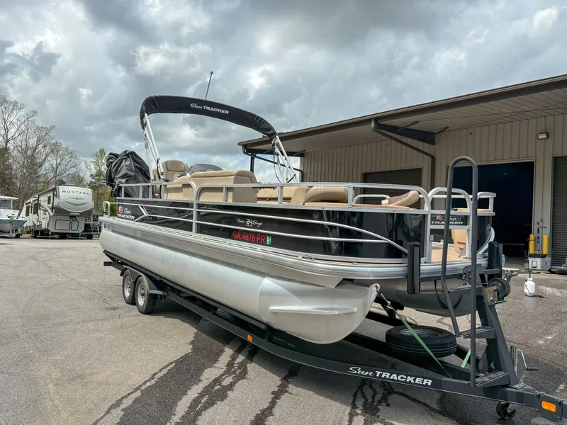 Slide: The Image of 2019 Sun Tracker Fishin Barge 24 DLX pontoon boat on trailer, parked outdoors. - 14