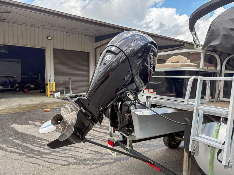 Slide: The Image of 2019 Sun Tracker Fishin Barge 24 DLX with outboard motor in a storage facility. - 17