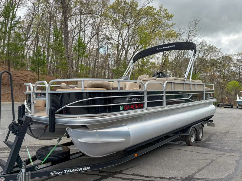 Slide: The Image of 2019 Sun Tracker Fishin Barge 24 DLX pontoon boat on trailer in wooded area. - 18
