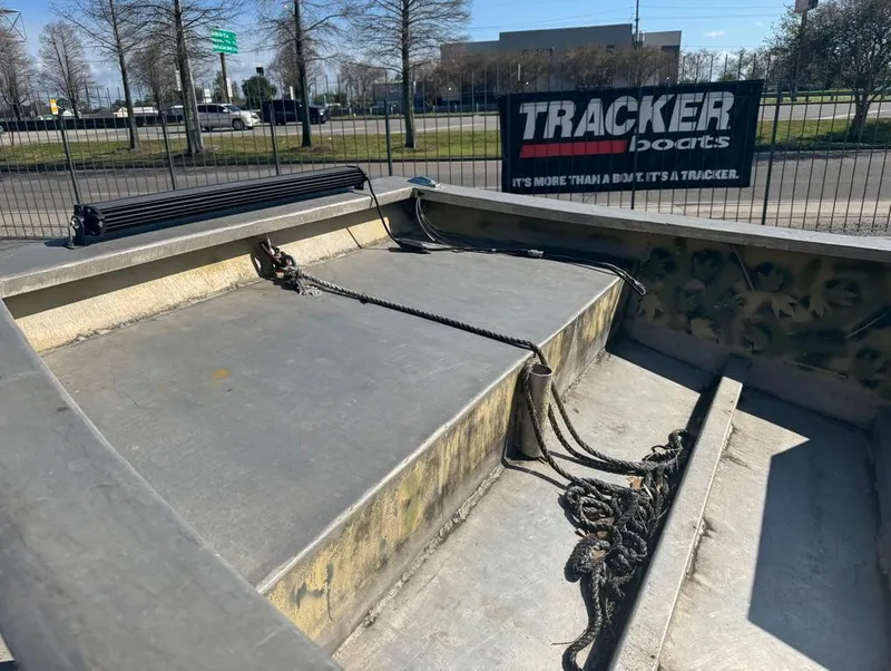 Slide: The Image of 1984 Custom Inboard Mud Boat with ropes, parked near Tracker Boats sign. - 10