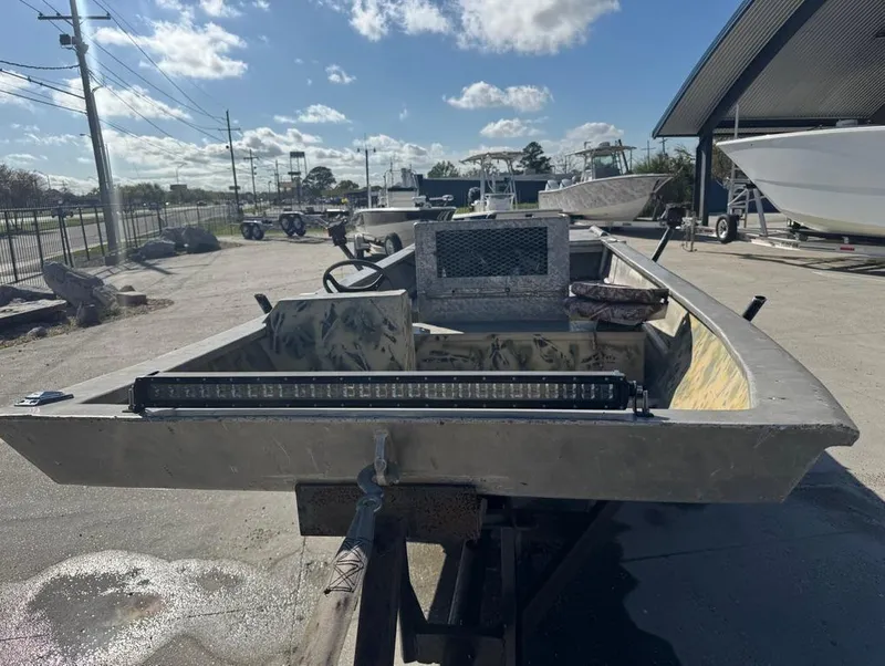 Slide: The Image of 1984 Custom Inboard Mud Boat on trailer under clear sky. - 11