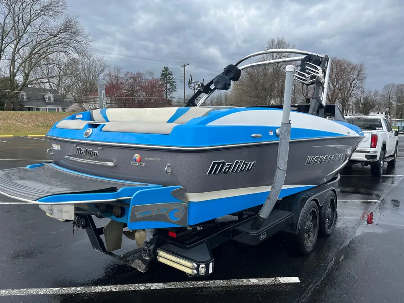 Slide: The Image of 2014 Malibu Wakesetter 24 MXZ boat in parking lot, blue and gray design. - 12