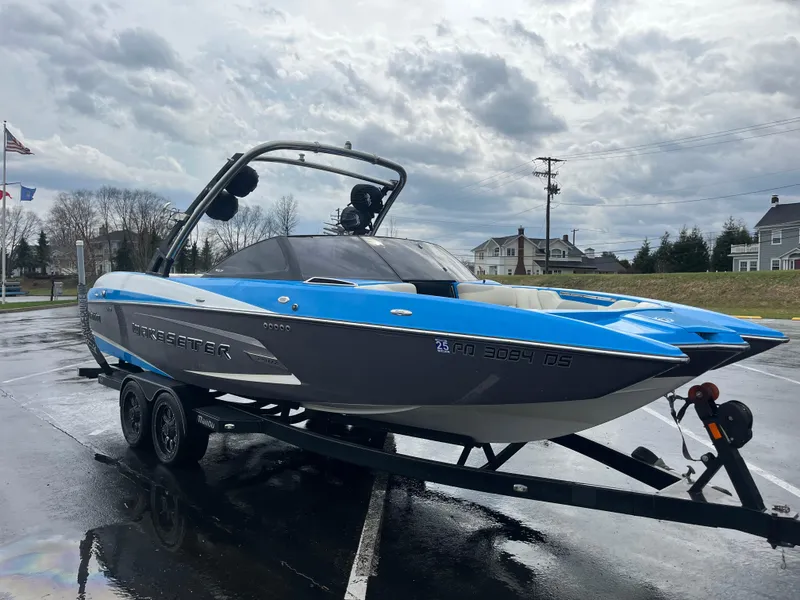 Slide: The Image of 2014 Malibu Wakesetter 24 MXZ boat on trailer, blue and gray, parked outdoors. - 13