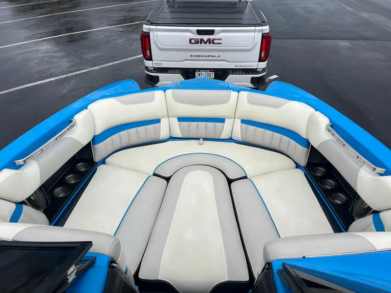 Slide: The Image of 2014 Malibu Wakesetter 24 MXZ boat interior with blue and white seating, parked near GMC truck. - 6
