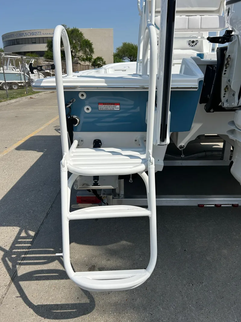 Slide: The Image of 2025 Shallow Sport 25 X3 boat with rear ladder and blue hull, parked on concrete. - 26