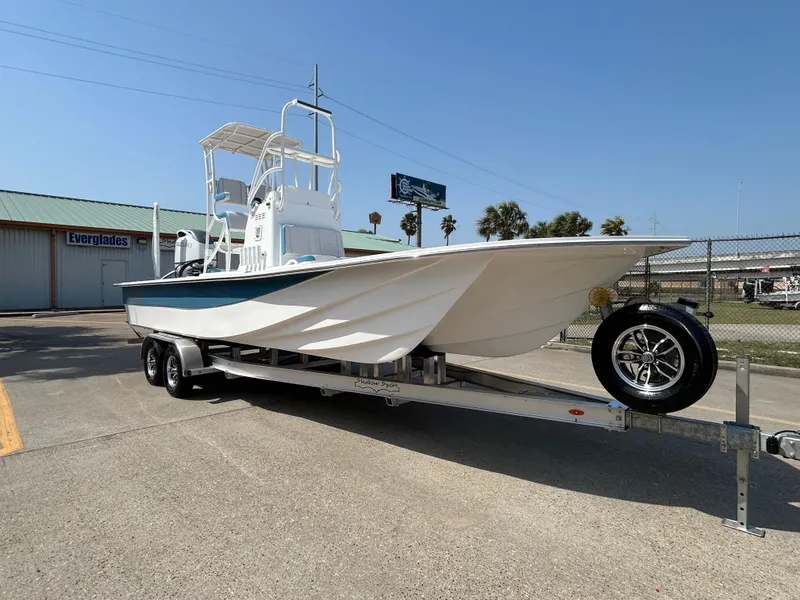 Slide: The Image of 2025 Shallow Sport 25 X3 boat on trailer, parked outdoors under clear sky. - 4