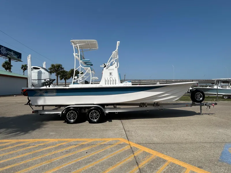 Slide: The Image of 2025 Shallow Sport 25 X3 boat on trailer, parked outdoors under clear blue sky. - 5