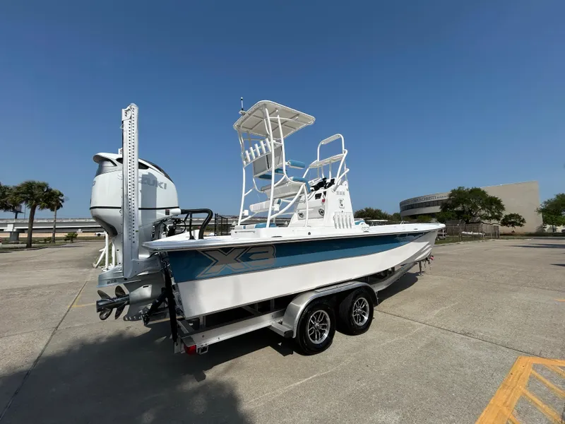 Slide: The Image of 2025 Shallow Sport 25 X3 boat on trailer, parked outdoors under clear blue sky. - 6