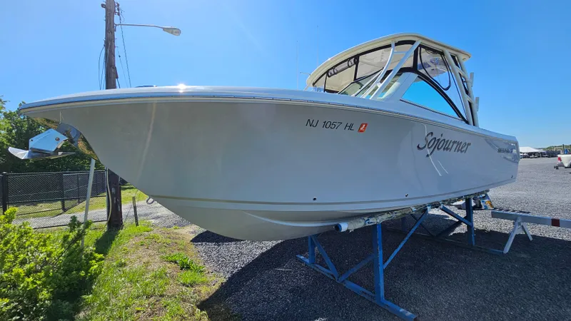 Slide: The Image of 2019 Sailfish 275 DC boat on trailer, side view under clear blue sky. - 2