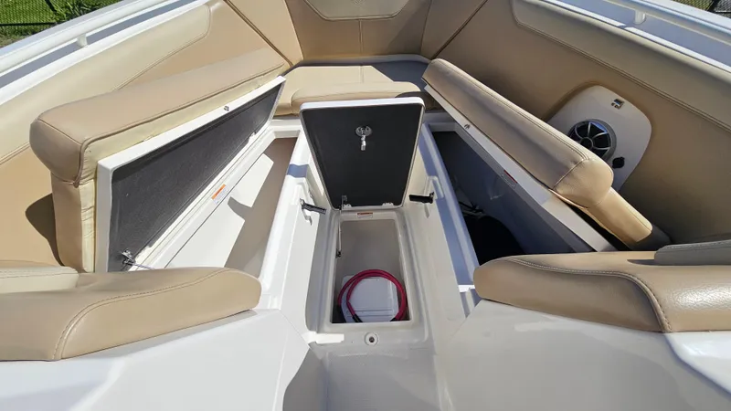 Slide: The Image of 2019 Sailfish 275 DC boat interior with open storage compartments and beige seating. - 36