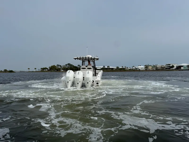 Slide: The Image of 2019 Fountain 34 CC boat with four engines cruising on a calm waterway. - 13