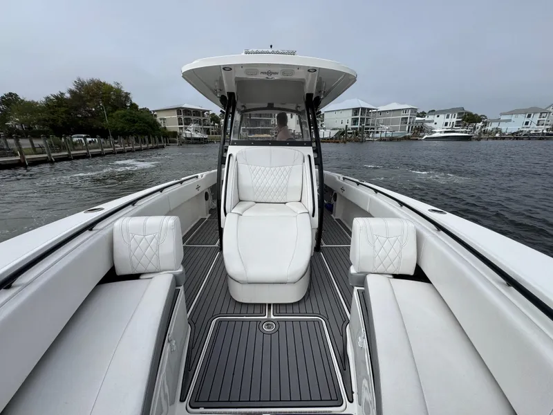 Slide: The Image of 2019 Fountain 34 CC boat with white seating, docked near waterfront homes. - 22