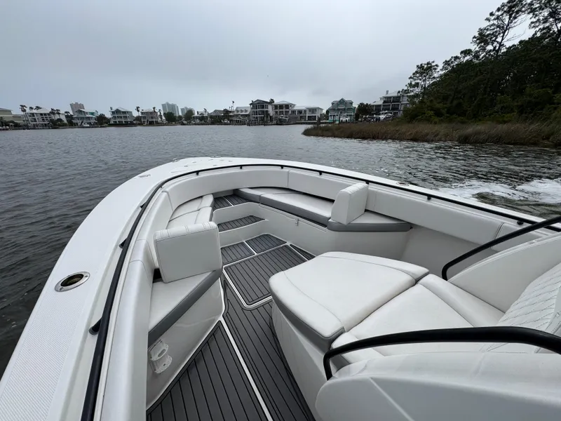 Slide: The Image of 2019 Fountain 34 CC boat with white seating, cruising on a calm lake near waterfront homes. - 23