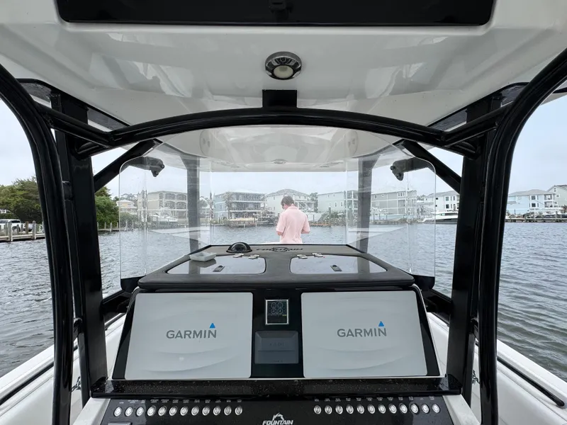 Slide: The Image of 2019 Fountain 34 CC boat interior with Garmin navigation, overlooking waterfront homes. - 30