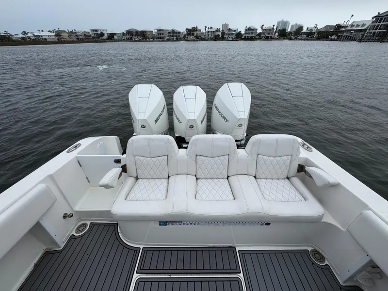Slide: The Image of 2019 Fountain 34 CC boat with triple outboard engines, luxurious seating, and waterfront view. - 35