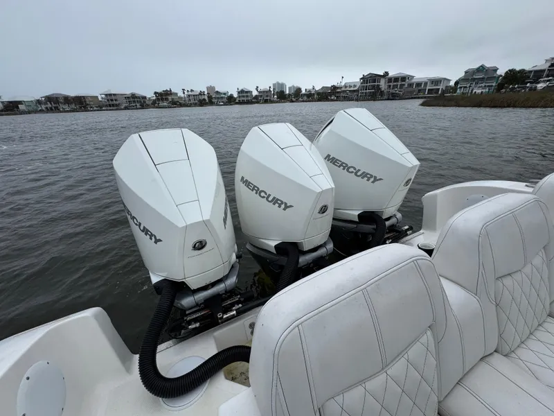 Slide: The Image of Triple Mercury outboard engines on a 2019 Fountain 34 CC boat, docked by waterfront homes. - 37