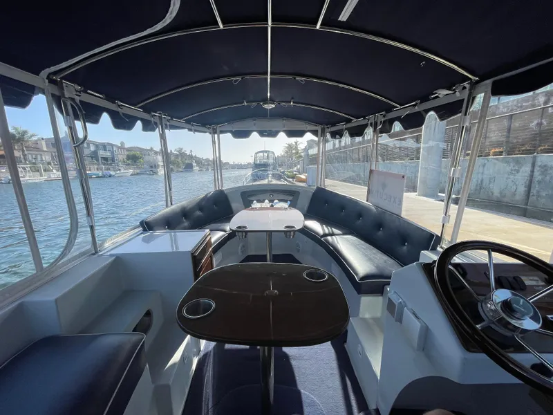 Slide: The Image of 2014 Duffy 18 Snug Harbor boat interior with seating and steering wheel, docked by waterfront homes. - 11