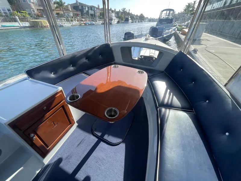Slide: The Image of Interior of a 2014 Duffy 18 Snug Harbor boat with seating and a wooden table. - 13