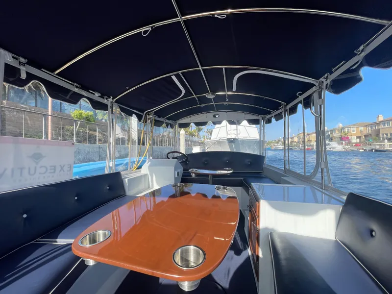 Slide: The Image of 2014 Duffy 18 Snug Harbor boat interior with seating and table on a sunny day. - 14