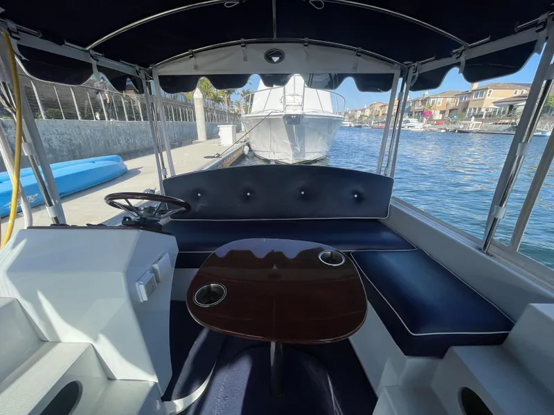 Slide: The Image of 2014 Duffy 18 Snug Harbor boat interior with seating and table, docked by waterfront homes. - 15