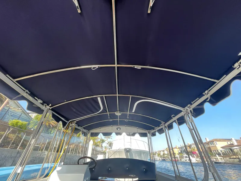 Slide: The Image of 2014 Duffy 18 Snug Harbor boat with blue canopy on a sunny day. - 19