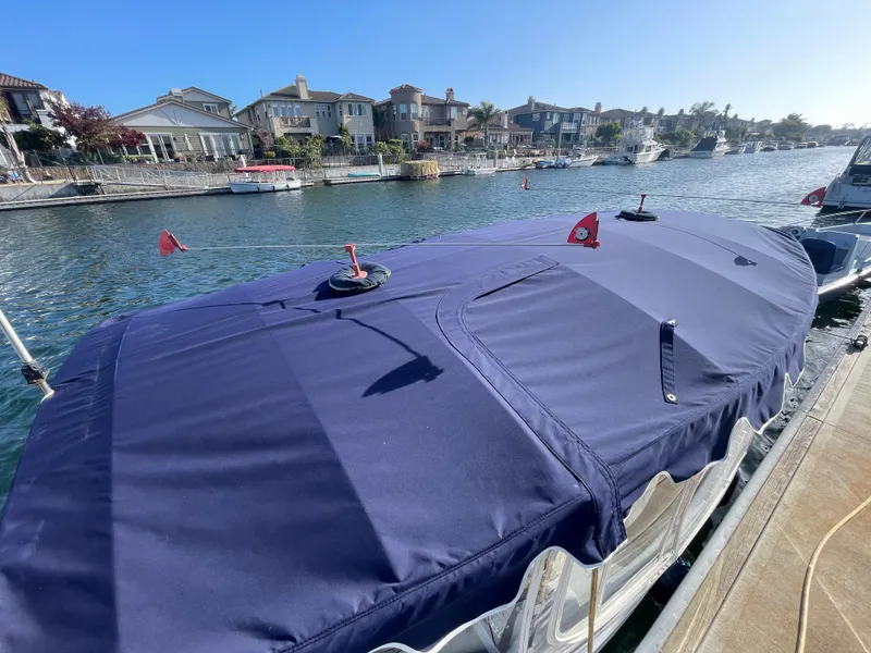 Slide: The Image of 2014 Duffy 18 Snug Harbor boat with blue cover docked in a scenic waterfront neighborhood. - 21