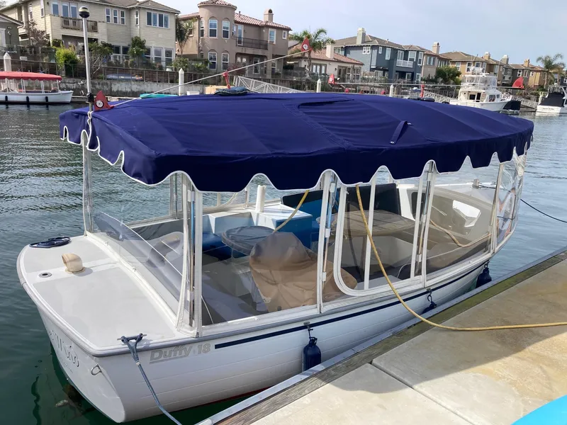Slide: The Image of 2014 Duffy 18 Snug Harbor electric boat docked in a marina with blue canopy. - 5