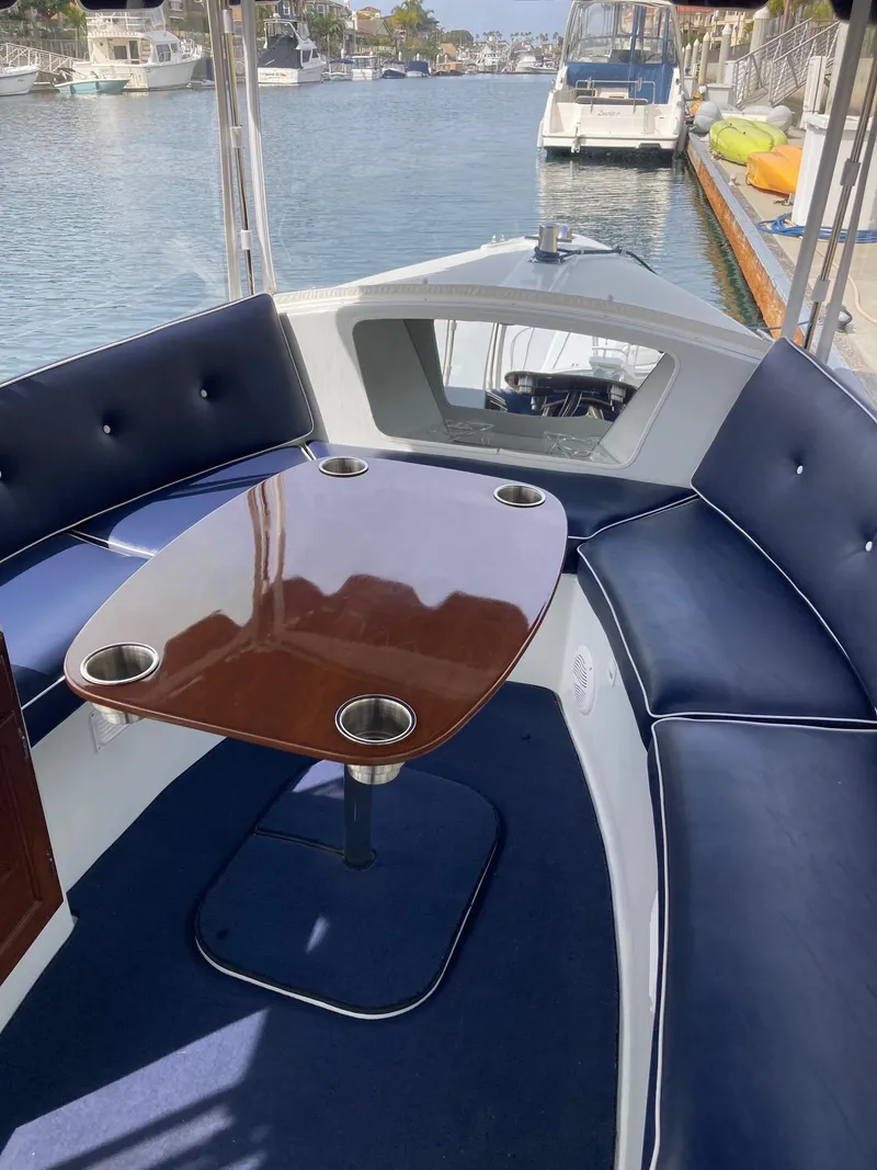 Slide: The Image of 2014 Duffy 18 Snug Harbor boat interior with blue seating and wooden table. - 7