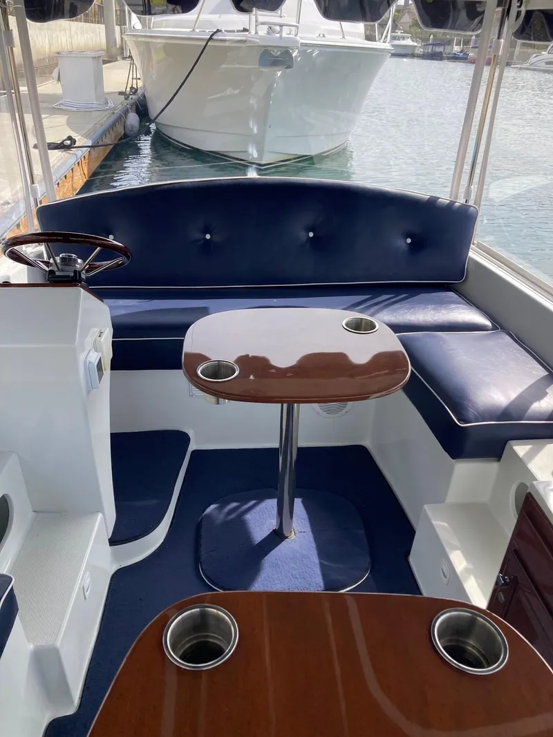 Slide: The Image of 2014 Duffy 18 Snug Harbor boat interior with blue seating and wooden table. - 8