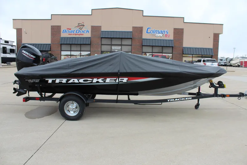 Slide: The Image of 2025 Tracker Pro Team 175 Crappie Edition boat with cover on trailer, parked outside dealership. - 7