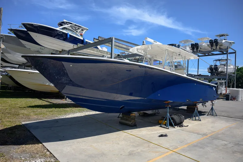 Slide: The Image of 2022 SeaVee 390Z boat in dry dock, blue hull, sunny day, multiple boats in background. - 1