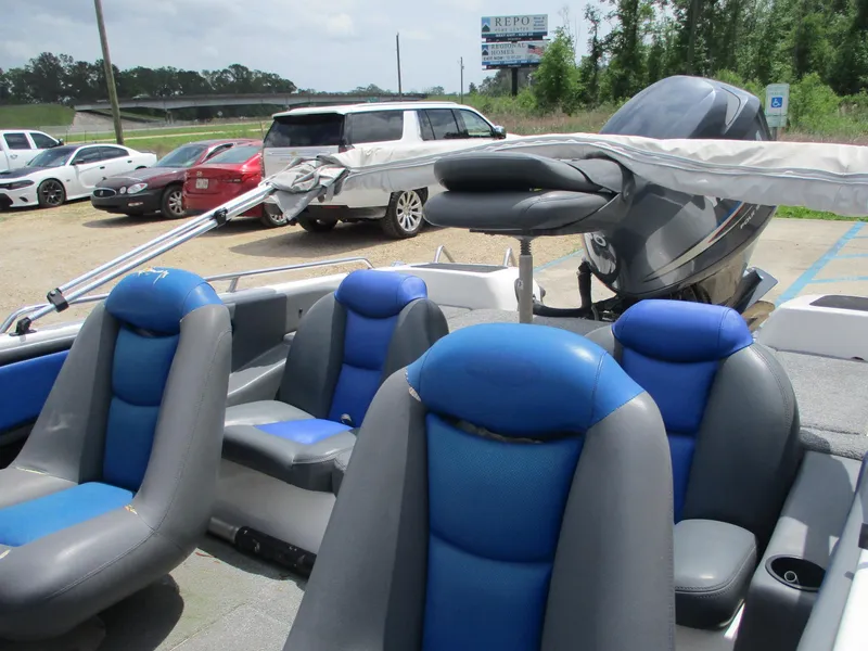 Slide: The Image of 2005 Skeeter SL 190 boat with blue and gray seating, parked near vehicles. - 10