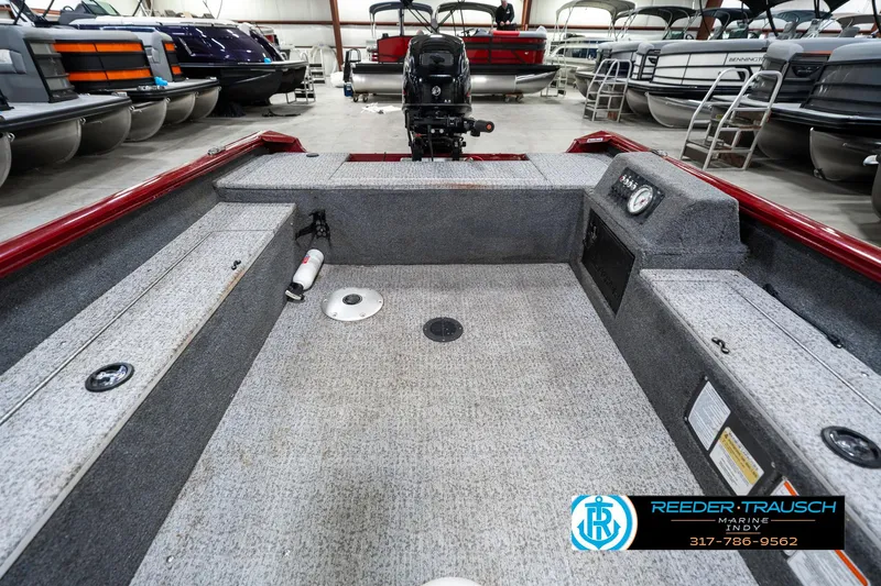 Slide: The Image of 2021 Tracker Super Guide 17 boat interior in showroom, featuring motor and seating area. - 18