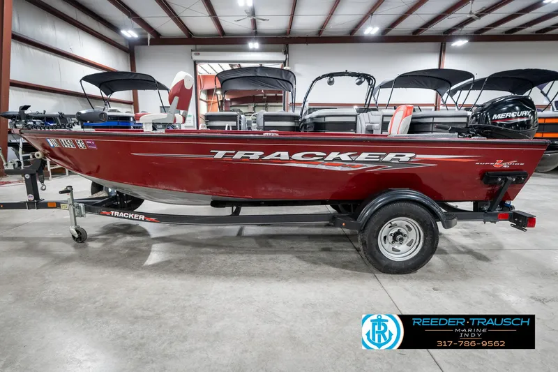 Slide: The Image of 2021 Tracker Super Guide 17 boat in showroom, red exterior, on trailer, with Mercury engine. - 9
