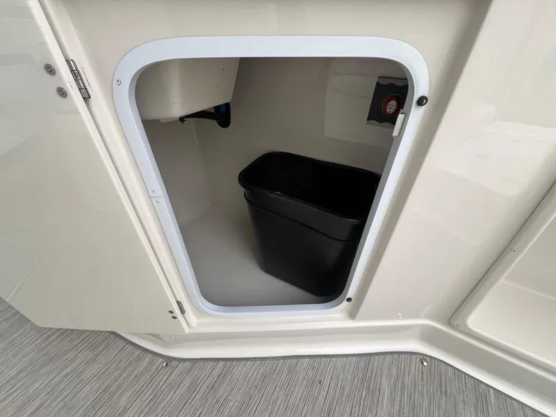 Slide: The Image of Storage compartment in a 2009 Monterey 254FS boat, featuring a black bin inside. - 26