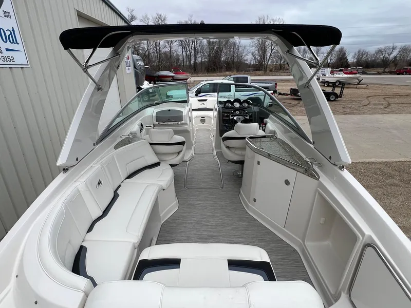 Slide: The Image of 2009 Monterey 254FS boat interior with white seating and black canopy, parked outdoors. - 7