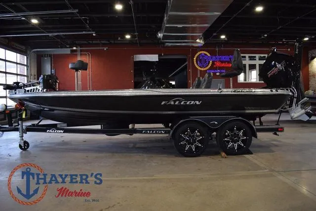 Slide: The Image of 2025 Falcon Bass Boats F20 TE in showroom, side view with trailer, Thayer's Marine logo visible. - 6