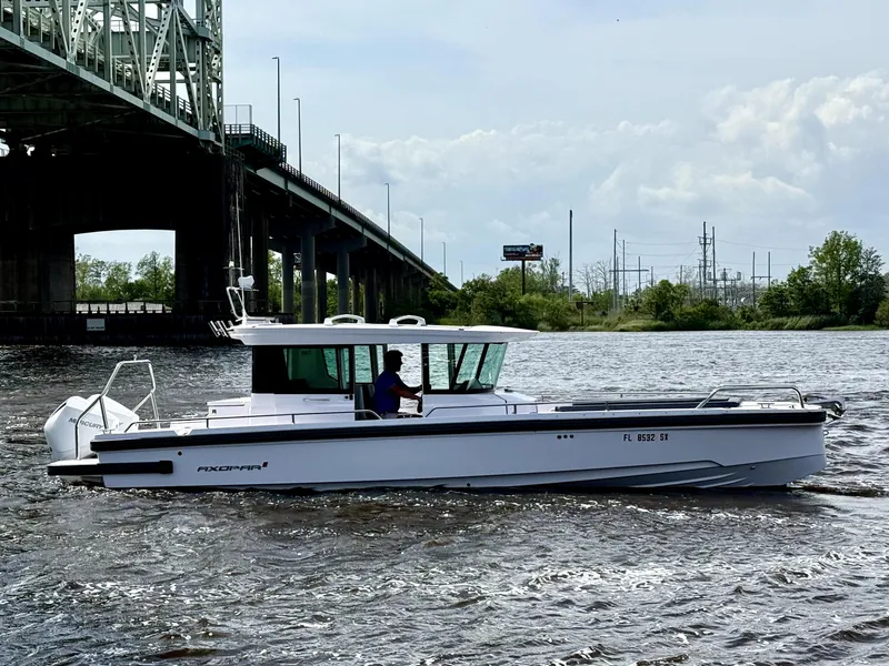 Slide: The Image of 2021 Axopar 28 CABIN boat cruising under a bridge on a river. - 0