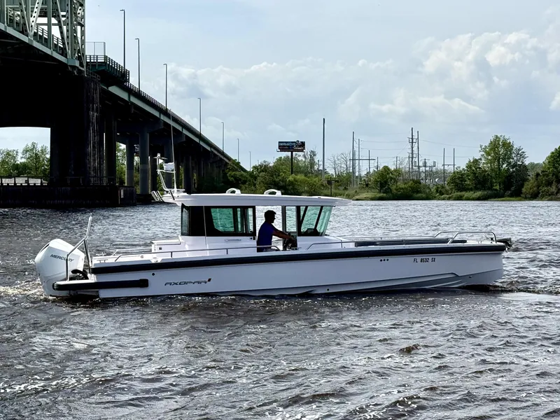 Slide: The Image of 2021 Axopar 28 CABIN boat cruising under a bridge on a river. - 1