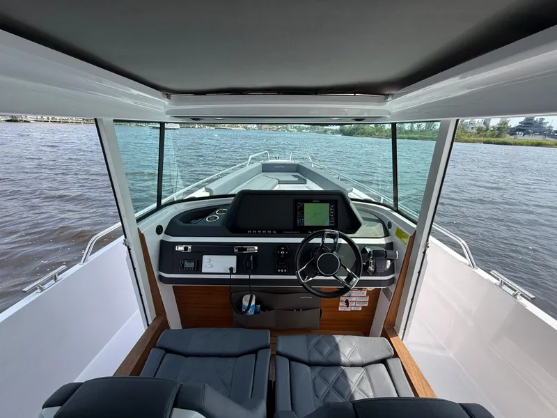 Slide: The Image of Interior view of 2021 Axopar 28 CABIN boat with modern dashboard and steering wheel. - 13