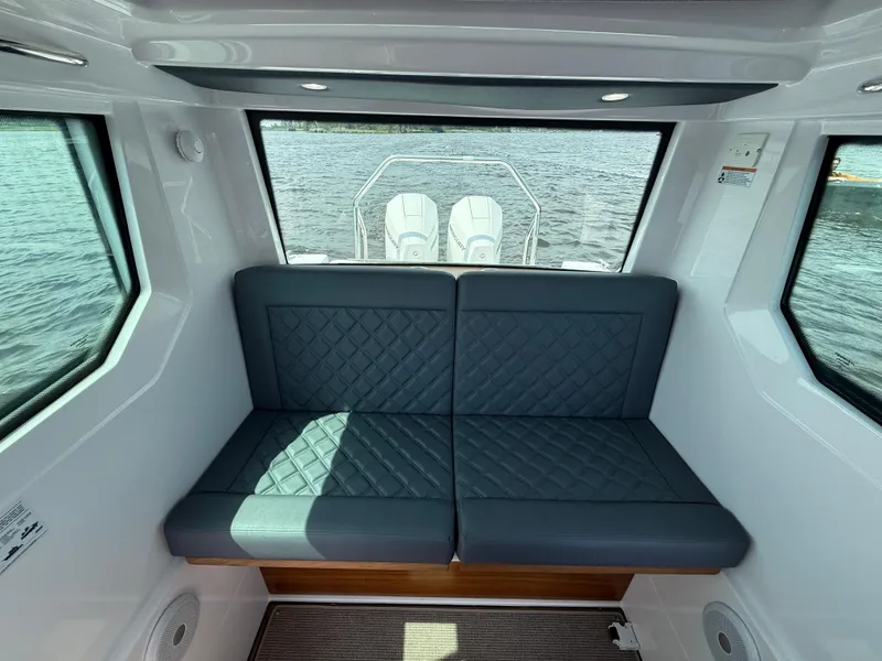Slide: The Image of Interior of 2021 Axopar 28 CABIN with cushioned seating and large windows overlooking water. - 16