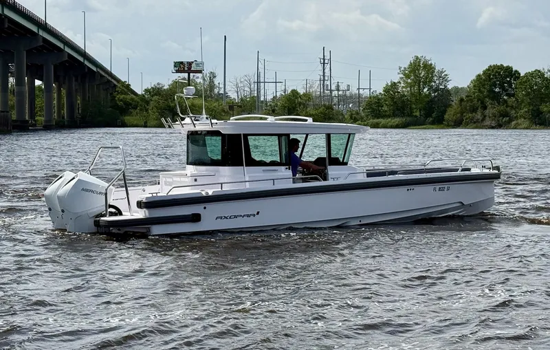 Slide: The Image of 2021 Axopar 28 CABIN boat cruising on a river near a bridge. - 2