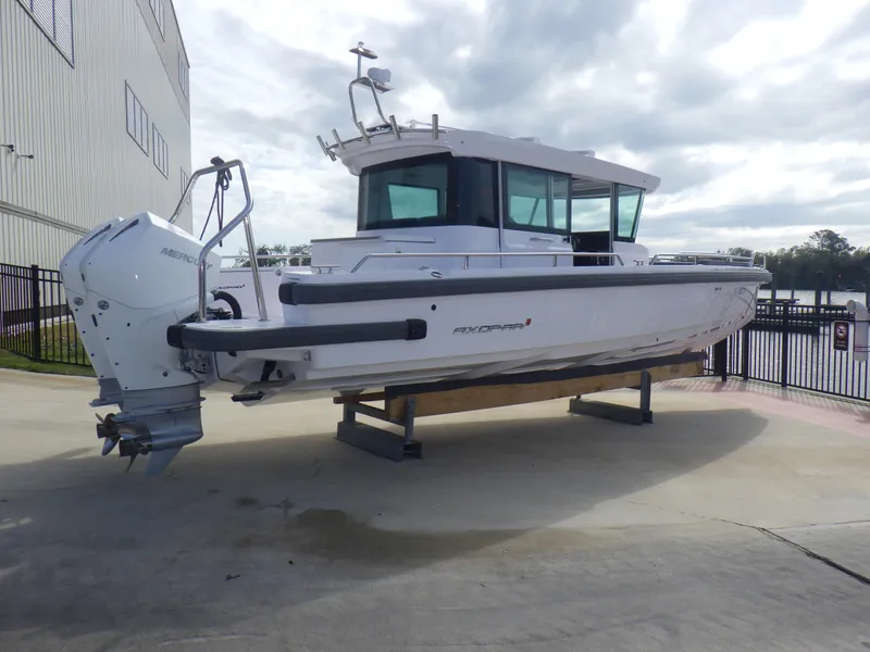 Slide: The Image of 2021 Axopar 28 CABIN boat on display, featuring sleek design and modern outboard motor. - 26