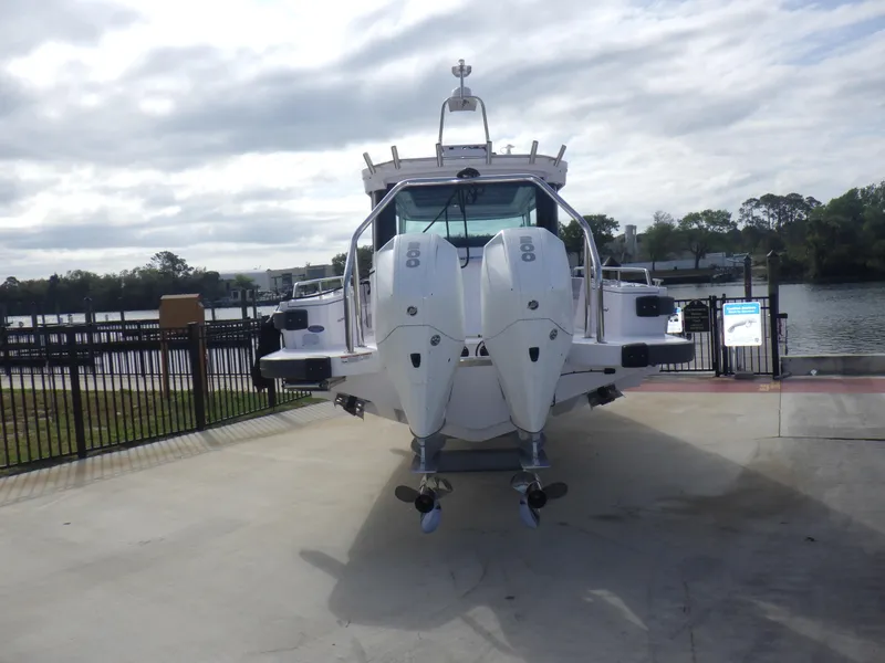 Slide: The Image of 2021 Axopar 28 CABIN boat with dual outboard engines, docked near a scenic waterfront. - 27