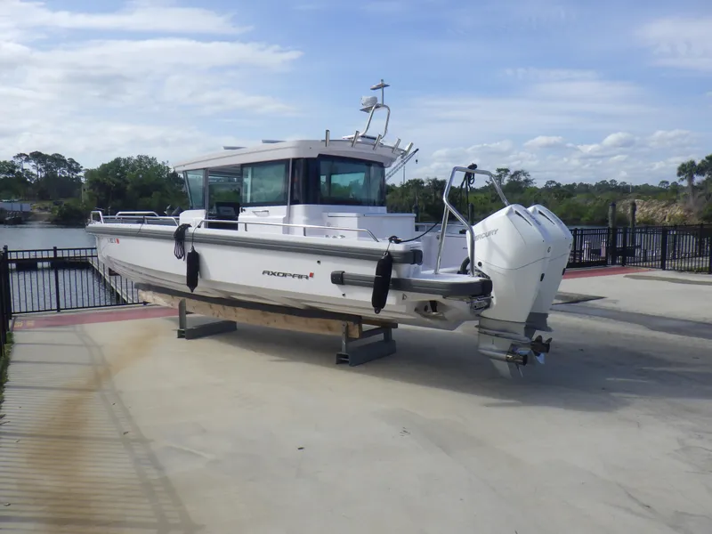 Slide: The Image of 2021 Axopar 28 CABIN boat on a dock, featuring twin outboard engines. - 28