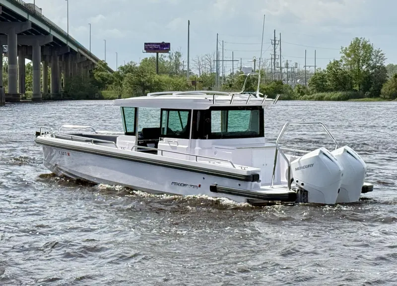 Slide: The Image of 2021 Axopar 28 CABIN boat cruising on a river near a bridge. - 3