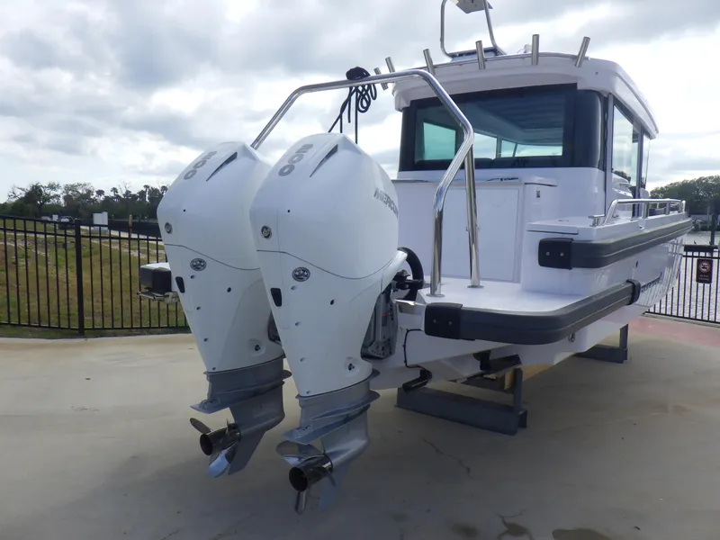 Slide: The Image of 2021 Axopar 28 CABIN boat with dual outboard engines, parked on a concrete surface. - 30