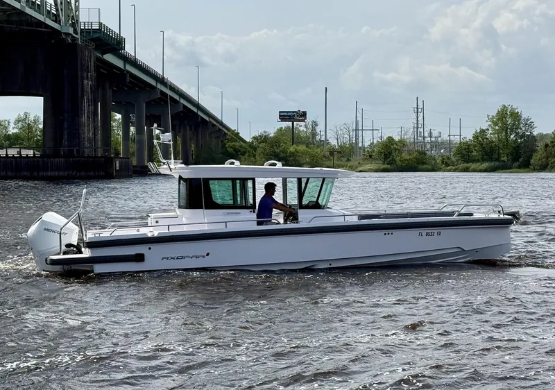 Slide: The Image of 2021 Axopar 28 CABIN boat cruising on a river near a bridge. - 4
